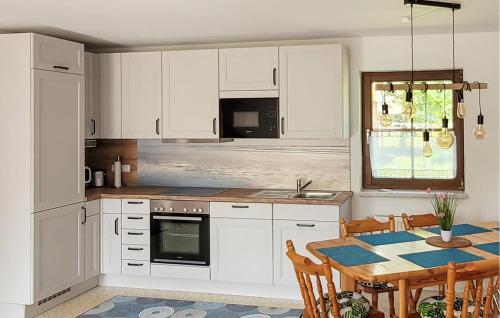 a kitchen with white cabinets and a table with chairs at Amazing Home In Prerow With Wifi in Prerow