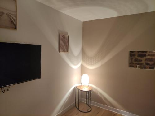 a room with a television and a table with a lamp at La vie est belle in Domjean