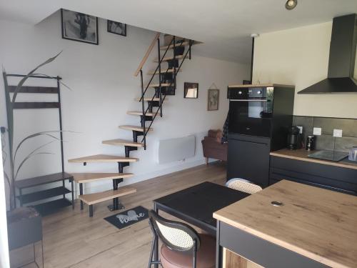 a room with a kitchen and a spiral staircase at La vie est belle in Domjean