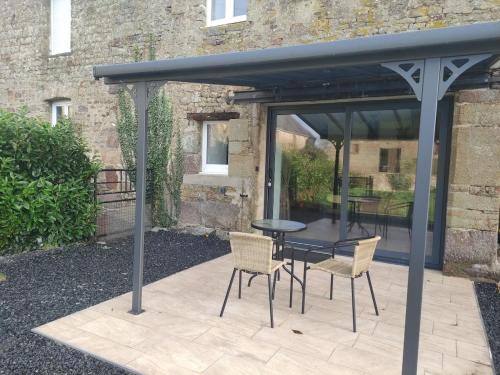 a black pergola with a table and chairs on a patio at La vie est belle in Domjean