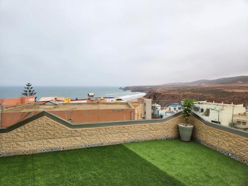 a stone wall with a green yard with a view of the ocean at Tirazir House 4 in Mirleft