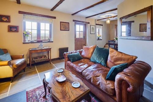 - un salon avec un canapé en cuir et une table basse dans l'établissement Romantic Country Cottage with log burner, garden patio, outdoor tub and country views- Brecon Beacons National Park, à Llangadog