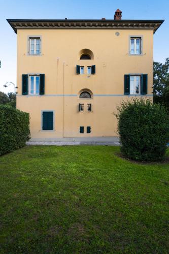 a large yellow building with windows and a yard at Villa Ines charme near Lucca in Altopascio