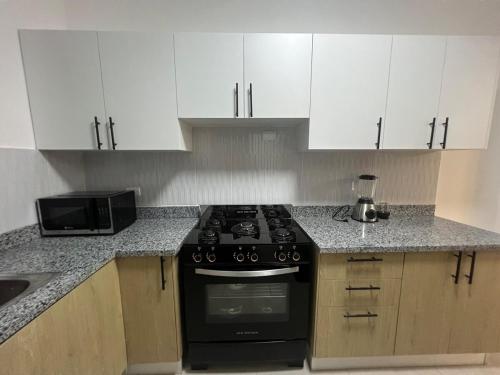 a kitchen with a black stove and white cabinets at Comfortable apartment in Los Mameyes