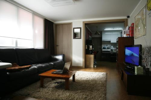 a living room with a black couch and a coffee table at Birdsnest Hostel Hongdae Foreigner only in Seoul
