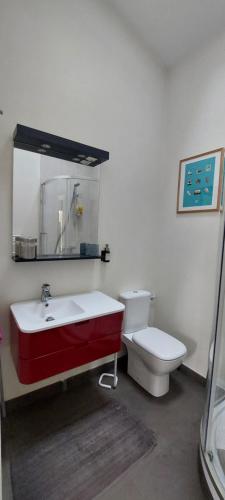 La salle de bains est pourvue d'un lavabo rouge et de toilettes. dans l'établissement Séjournez chez Cédric et Julie, à Montesson