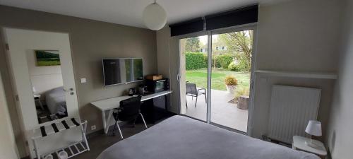 une chambre avec un lit, un bureau et une télévision dans l'établissement Séjournez chez Cédric et Julie, à Montesson