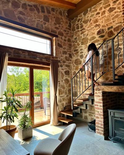 a person sitting on the stairs in a room with a stone wall at Kompleks Etno Luks in Crvulevo
