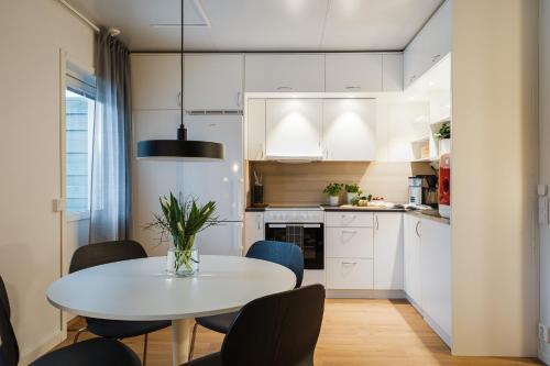 a small kitchen with a white table and chairs at Guestly Homes - 1BR Scandinavian Charm in Piteå
