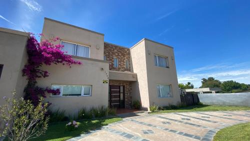 a house with purple flowers in front of it at Urano Pinamar in Pinamar