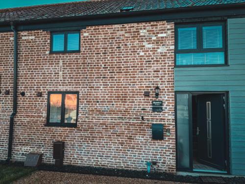 a brick building with blue windows and a door at Bramble Barn Carlton Colville Lowestoft 8 Guests in Carlton Colville