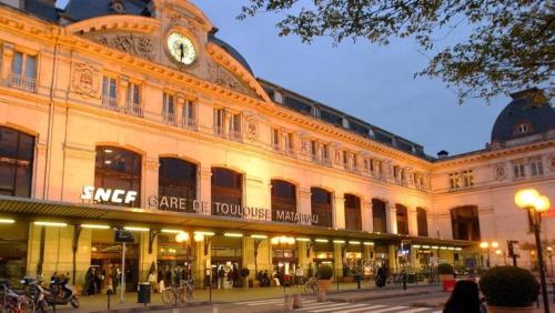 un grand bâtiment avec une horloge en haut dans l'établissement studio balcon toulouse gare, à Toulouse