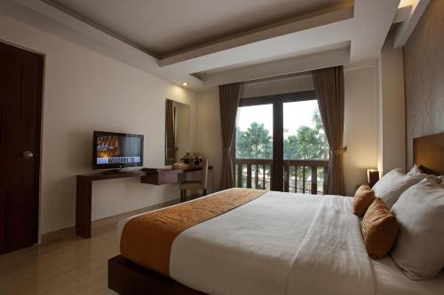 a bedroom with a large bed and a window at d'primahotel Seminyak in Seminyak