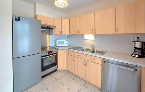 une cuisine avec des armoires en bois et un réfrigérateur en acier inoxydable dans l'établissement Lovely Home In Gérardmer With Kitchen, à Gérardmer