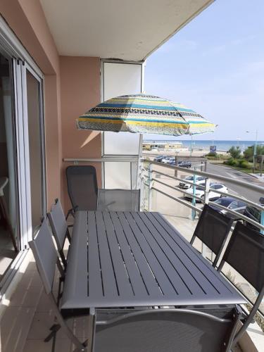 une table et des chaises sur un balcon avec un parasol dans l'établissement Appartement face mer Rêve de Flo ts, à Saint-Jean-de-Monts