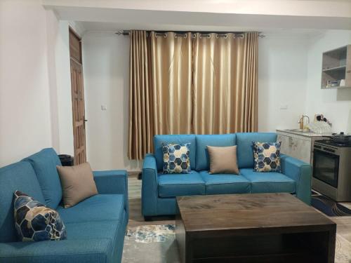 a living room with a blue couch and a table at Pine 2 bedroom apartment with a pool in Nanyuki
