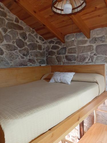 a bed in a room with a stone wall at Casa da mestre in Crecíente
