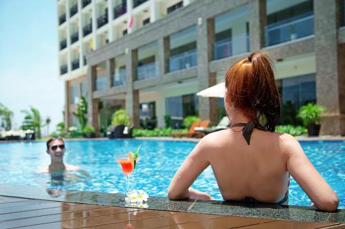 a woman sitting in the swimming pool with a drink at Muong Thanh Holiday Hoi An Hotel in Hoi An