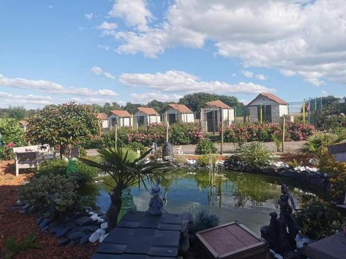 a pond in a garden with houses in the background at gîte dans endroit atypique in Flamets-Frétils