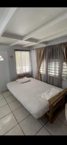 a large bed in a room with two windows at Boquerón Beach & Country Cabins in Boqueron