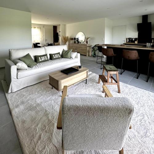 a living room with a white couch and a piano at L'Ambroisie in Bréhal
