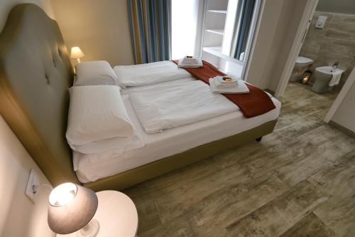 a bedroom with a bed with white sheets and a window at La Dolce Vita Relais - Hotel Gallo in Tignale