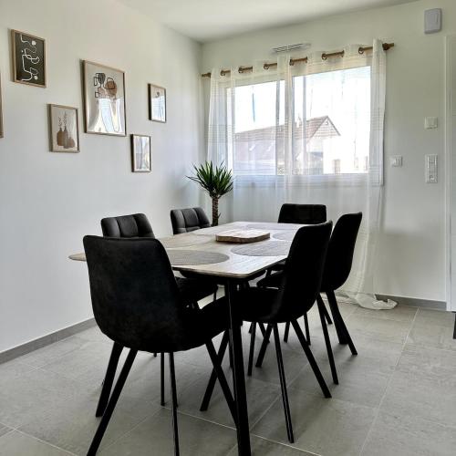 a dining room with a table and black chairs at L'Ambroisie in Bréhal