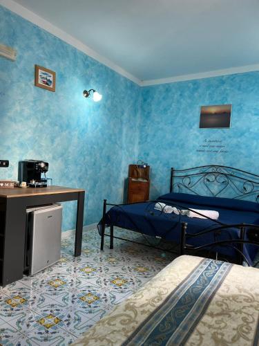 a bedroom with two beds with blue walls and a desk at Casa Vacanze Central Cincotta in Lipari