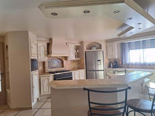 une cuisine avec des armoires blanches et un comptoir dans l'établissement Maison avec piscine 10 personnes, à Chambajour