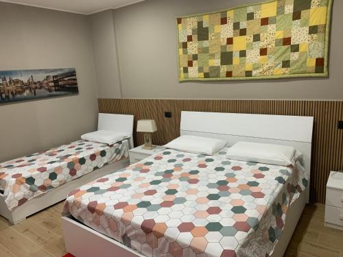 a bedroom with two beds and a quilt on the wall at Bed & Breakfast Indi Thelar in Villa Guardia