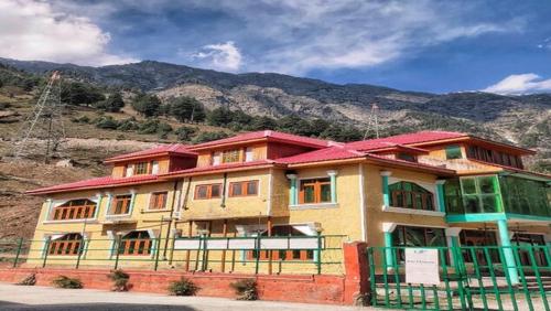 a building with a fence in front of a mountain at Hotel Relax Inn in Nichinai