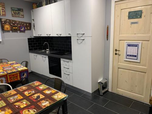a kitchen with white cabinets and a table and a door at Bed & Breakfast Indi Thelar in Villa Guardia