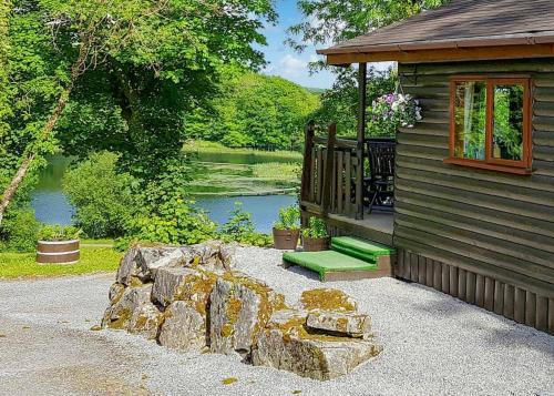 a log cabin with a porch and a rock wall at Garnffrwd Cottages in Llanddarog