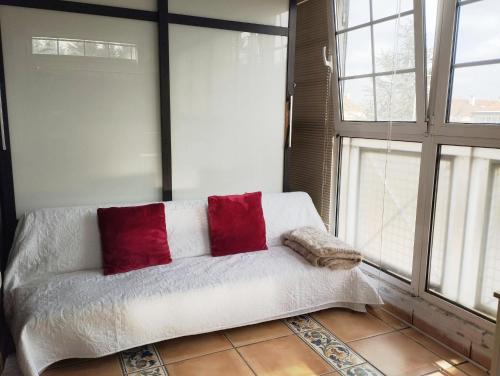 a white bed with red pillows in a room with windows at Home stay ideal for bikes and walking the camino in Zizur Mayor