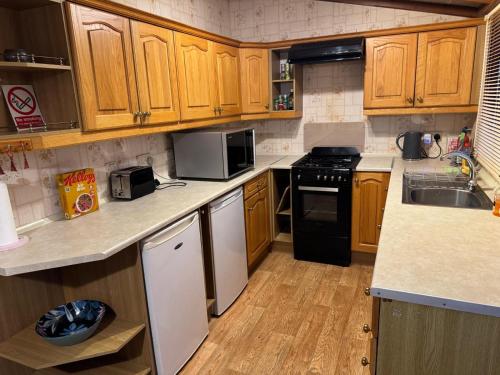 a kitchen with wooden cabinets and black appliances at Huntersfield Chalet in Faringdon