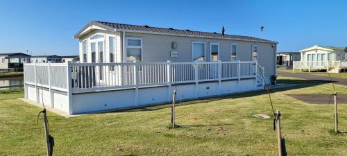 a house with a white fence in a yard at Golden Anchor Holiday Park- Europa Sequoia Private Static Caravan Hire - Wildflower Meadow - Chapel St Leonards in Chapel Saint Leonards