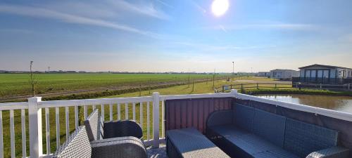 a balcony with two chairs and a view of a field at Golden Anchor Holiday Park- Europa Sequoia Private Static Caravan Hire - Wildflower Meadow - Chapel St Leonards in Chapel Saint Leonards