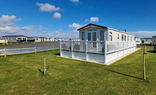 a small house with a porch on the grass at Golden Anchor Holiday Park- Europa Sequoia Private Static Caravan Hire - Wildflower Meadow - Chapel St Leonards in Chapel Saint Leonards