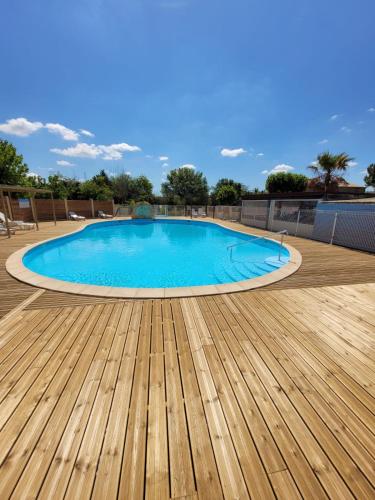 une grande piscine avec une terrasse en bois dans l'établissement Camping Les Peupliers, à Colombiers