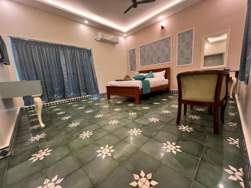 a bedroom with a bed and a chair at Le French Nest in Puducherry