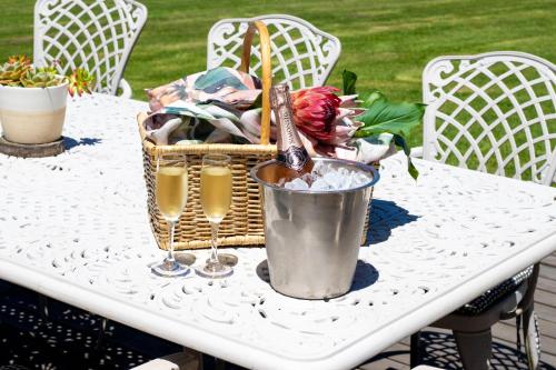 a table with two glasses of wine and a basket of flowers at The Cacoon Tsitsikamma in Stormsriviermond