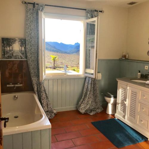 une salle de bain avec baignoire et une grande fenêtre dans l'établissement Villa provençale moderne, à Vercoiran