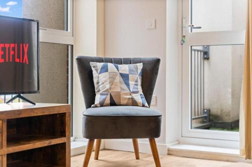 a chair with a pillow on it next to a window at Tranquil Telford Retreat with 2 Bedrooms in Telford