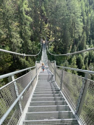 a woman walking across a suspension bridge in a forest at Bergblick rundum Zirl by Base&Beyond in Zirl