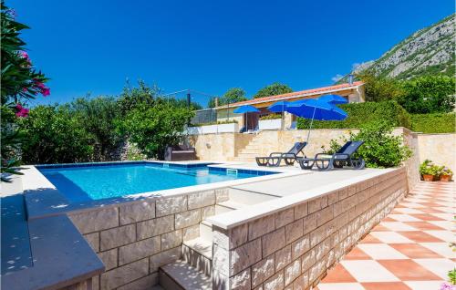 a swimming pool with two chairs and a house at Cozy Apartment In Dubravka With Sauna in Gruda
