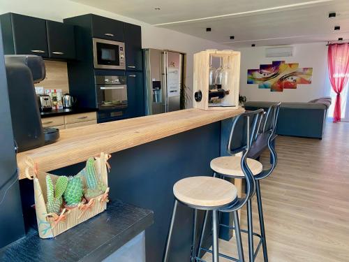 une cuisine avec deux tabourets de bar et un comptoir dans l'établissement Can FRANCES - Parking-Garage-2 jardins-Terrasse-BRASERO-MER-Wifi, à Villelongue-de-la-Salanque