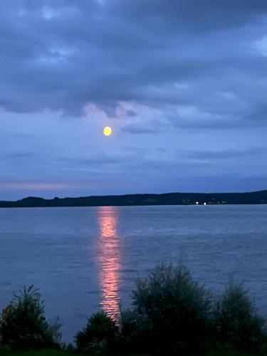 a moon rising over a large body of water at Fewo am Plöner See in Ascheberg