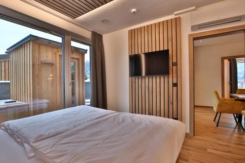 a bedroom with a bed and a television and a desk at Das Goldjuwel - Luxury Apartments with private Spa in Goldegg