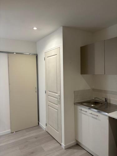 une cuisine avec des placards blancs et une porte blanche dans l'établissement La Cigalière 2 charmant T2 avec terrasse dans villa, à Solliès-Ville