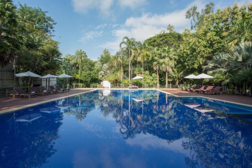 a swimming pool with blue water and palm trees at Kaomai Lanna Resort in San Pa Tong